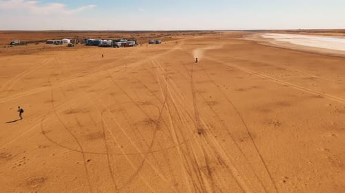 A motorcyclist returns to a moto camp in the desert after a race. Moto festival. View from above.