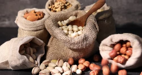 Different types of nuts in bags on black table, closeup