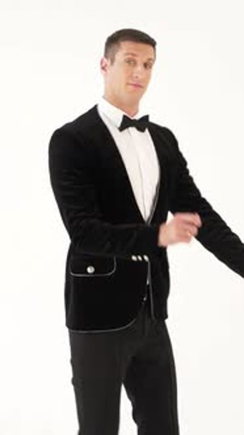 hombre divertido en un traje negro con una pajarita está mostrando el baile de la bailarina sobre el fondo blanco