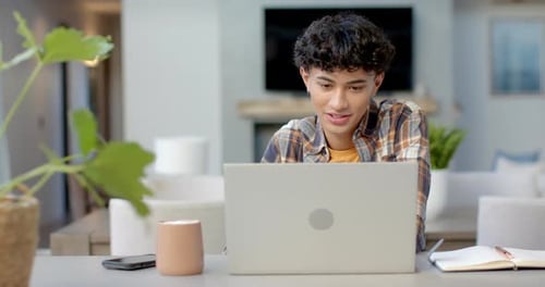 Teen Boy Works On Laptop At Home At Desk