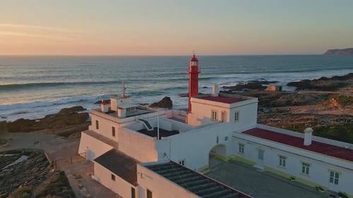 Panoramischer Sonnenuntergang, Leuchtturm, stehende felsige Küste, Luftaufnahme
