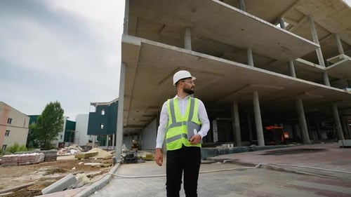 Civil Engineer Walking with Laptop at Construction Site