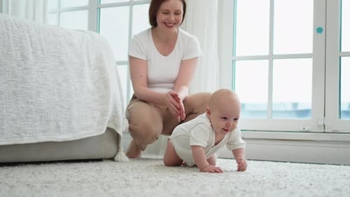 Happy Family Mother Father Looking at Cute Little Toddler Girl Crawling on Floor in Bedroom Infant