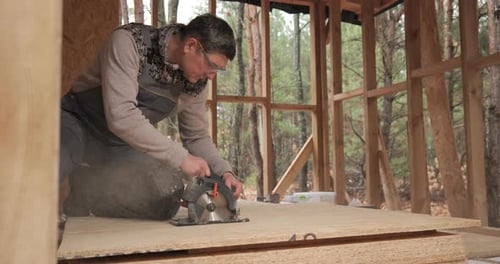 A Worker Uses a Circular Saw to Cut Plywood