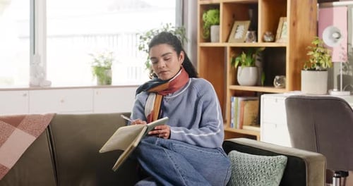 Woman Writing in Notebook on Couch at Home