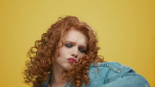 Expressive young woman with red hair dances in studio