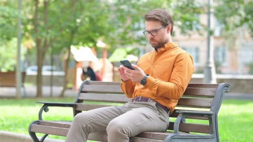 Young Adult Using Phone on Park Bench