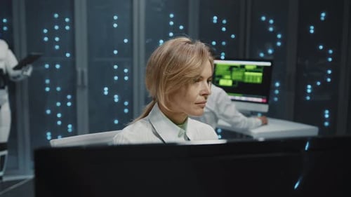Blonde IT Administrator Woman Using Computer Browsing Server Data Working at Data Center Robots and