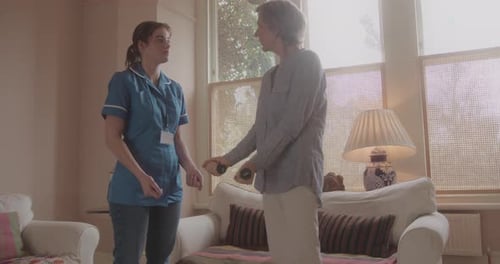 Senior Woman Exercises with Dumbbells Assisted by Nurse