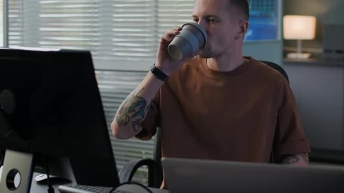Man Working at Computer and Drinking Coffee