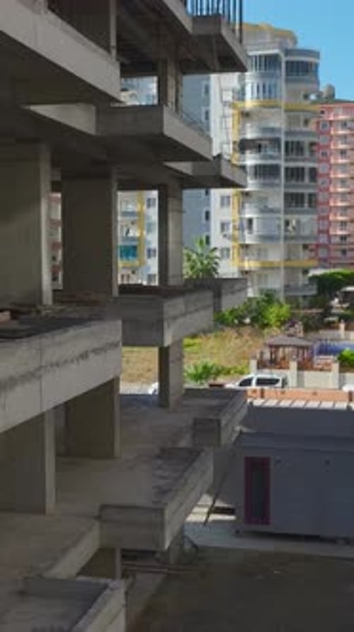 Vertical Video Aerial View Of Workers Constructing A Tower Crane On A Vibrant Worksite Captured With