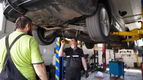 Professional Repairmen Doing Technical Inspection and Diagnostic of Vehicle at Garage Male Auto