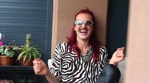 Non-binary influencer laughing and having fun on a balcony