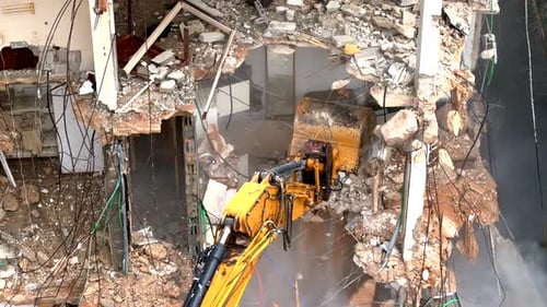 Excavator arm demolishing an old building, Aerial view