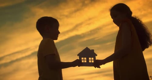Boy and Girl Holding House Cutout at Sunset