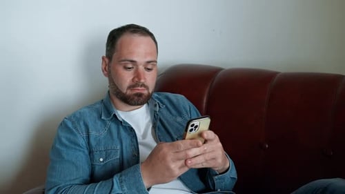 Man Using Smartphone While Sitting on Sofa