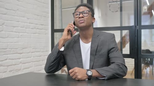 Young Adult Talks on Cellphone in Modern Office