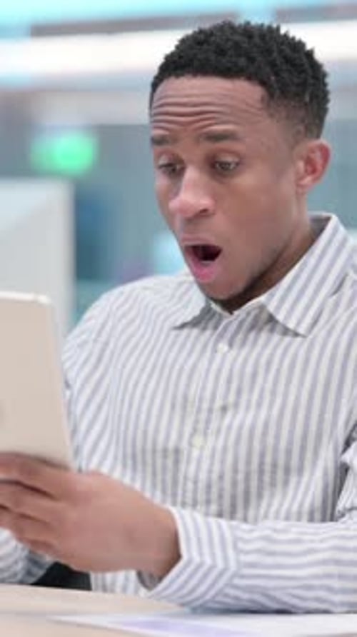 Surprised Young Man Looking at Tablet in Office