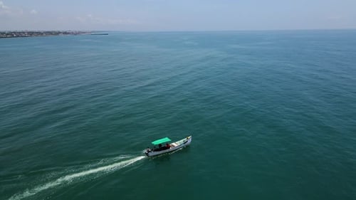 Atemberaubende Drohnenaufnahme aus der Luft, die ein Fischerboot inmitten des ruhigen blauen Ozeans einfängt.