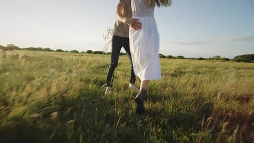 Young Couple Enjoys Summer Afternoon Running Across Field