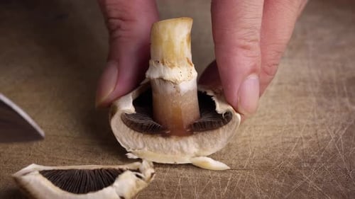 Slicing Champignon Mushroom on Wooden Table with Knife Food Preparation Close Up