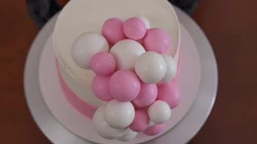 Top View Spinning Delicious Pink and White Cake with Sugar Balls Decoration on Table