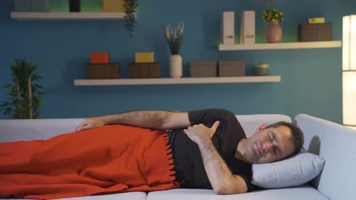 Homme au lit riant devant la caméra.