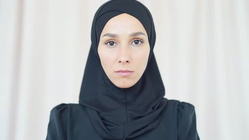 Woman Wearing Black Head Covering Stares at Camera