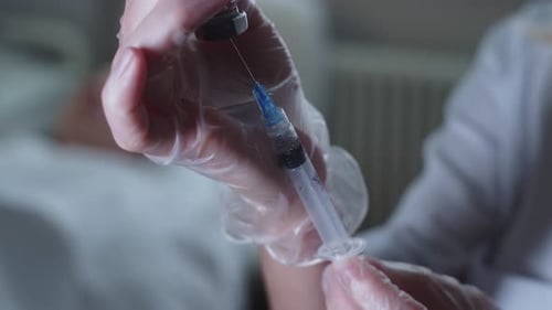 Medical Professional Preparing Injection with Syringe