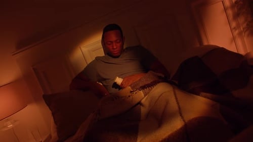 Man Sitting in Bed Examines Pill Bottle