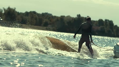 Junger Mann beim Wake-Surfen auf Flusswellen und trainiert Extremwassersport in Zeitlupe