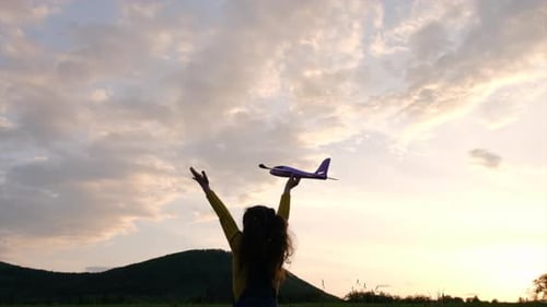 Girl Holding Airplane Toy at Sunset