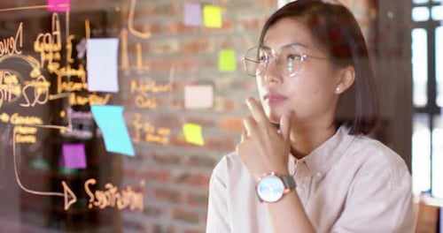 Thoughtful asian creative businesswoman brainstorming ideas in casual office, slow motion
