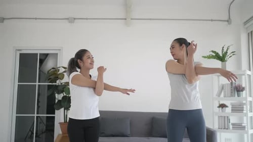 Two Women Stretching Arms Together Indoors
