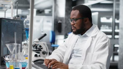 Focused Scientist Typing at Computer in Modern Lab
