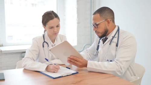 Doctors Reviewing Patient Information on Tablet and Notes