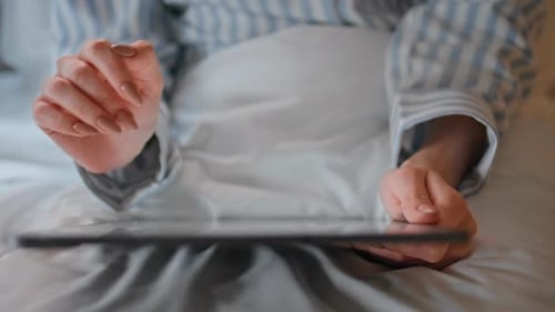 Woman Hands Swiping Tablet on Cozy White Bed Closeup Woman Planning Work on Pad