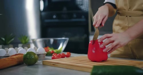 Close up unknown woman cutting on pepper with knife on cutting board when preparing vegetable salad
