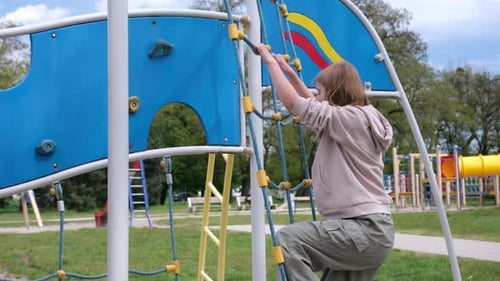Cute Little Girl Climbs On A Kid's Playground After School