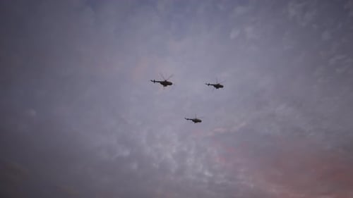 Three Helicopters Fly in Formation Across a Cloudy Sky