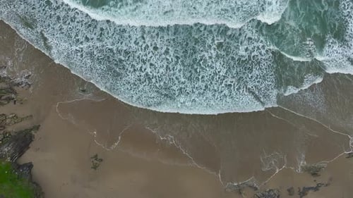 Bird's Eye View Of Foamy Waves On The Sandy Shore Of The Beach - Drone Shot, Slow Motion
