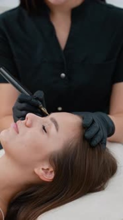 Woman Receiving Eyebrow Microblading Cosmetic Treatment