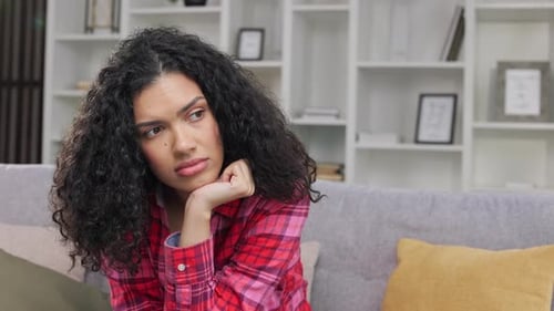 Pensive Woman with Curly Hair Thinking at Home