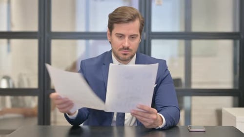 Young Businessman Reading Documents in Office