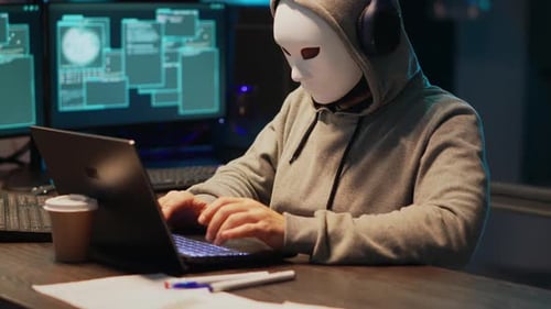 Un escroc masqué masculin vole des informations dans un programme de base de données