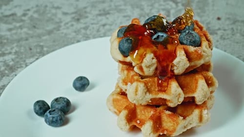 Syrup being poured on Waffles with Blueberries