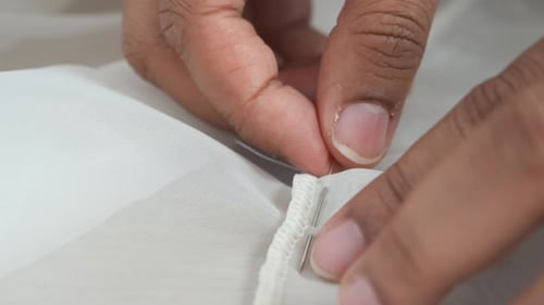 Close Up of Hands Sewing White Fabric