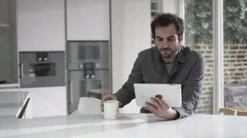 Man Using Tablet Device and Drinking Coffee
