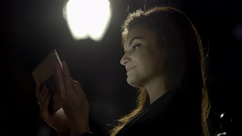 Young Woman Using Tablet Computer In The Park At Night