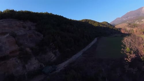 Areal shot of rally car driving fast under a hill on dirt track